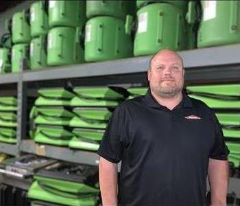 Image of male employee with black polo and green background