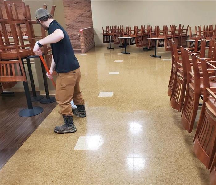 male staff member in black shirt mopping floor